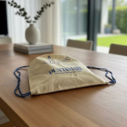 Dettaglio lifestyle della sacca in fibra naturale Puntamari su un tavolo in legno, simbolo di un gin sostenibile italiano